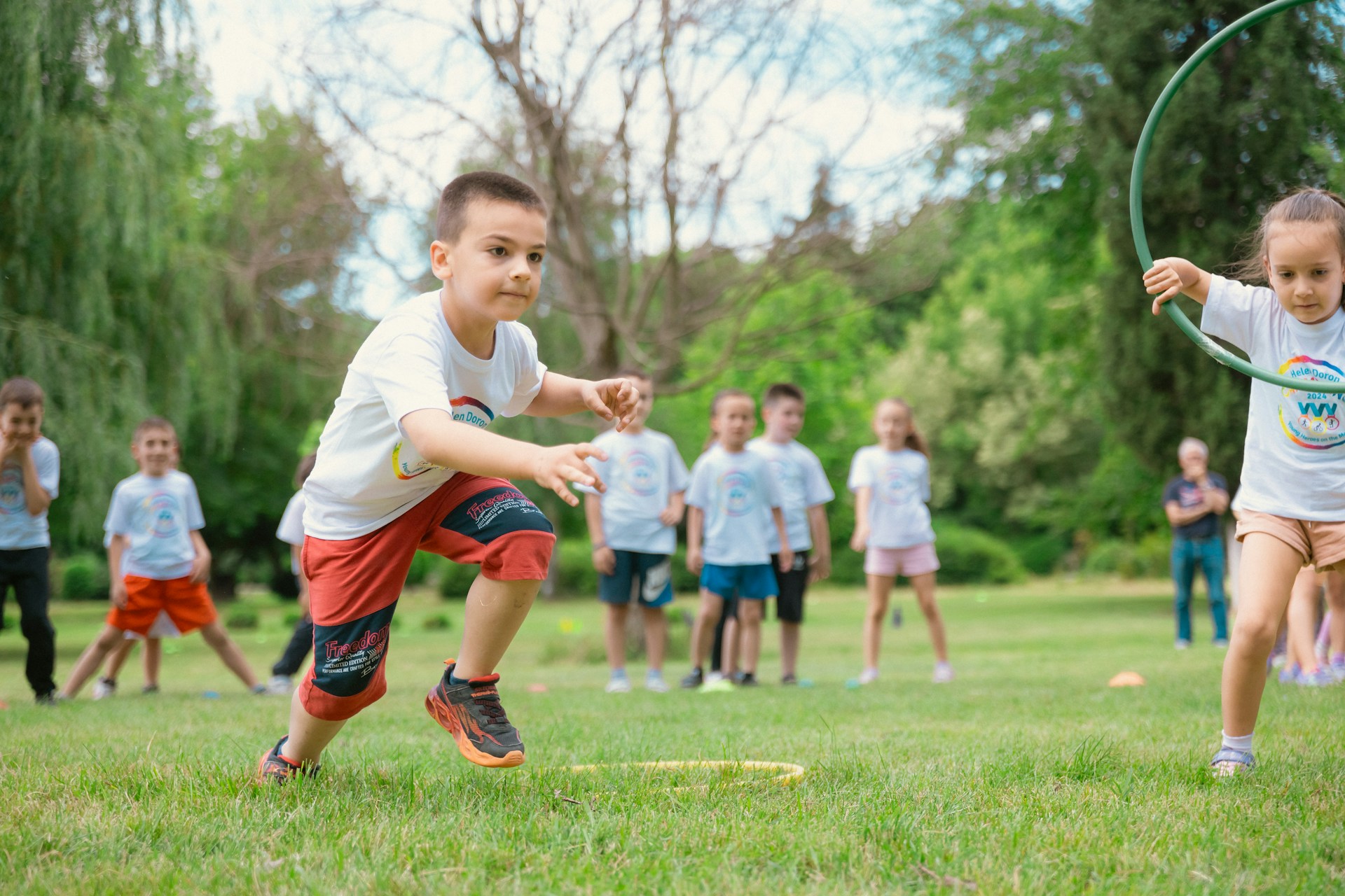 children playing on a green field surrounded by trees