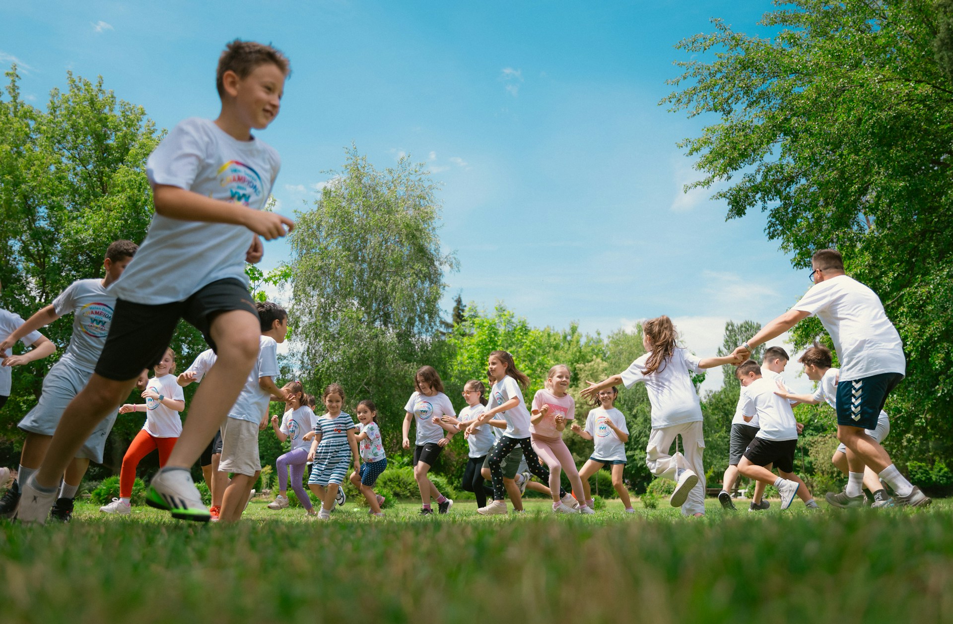 children playing on a green field surrounded by trees